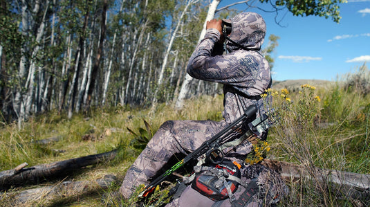 Hunter glassing big country with tripod using a Ditty Bag for optics accessories and a Hunter’s Tarp as a dry glassing platform