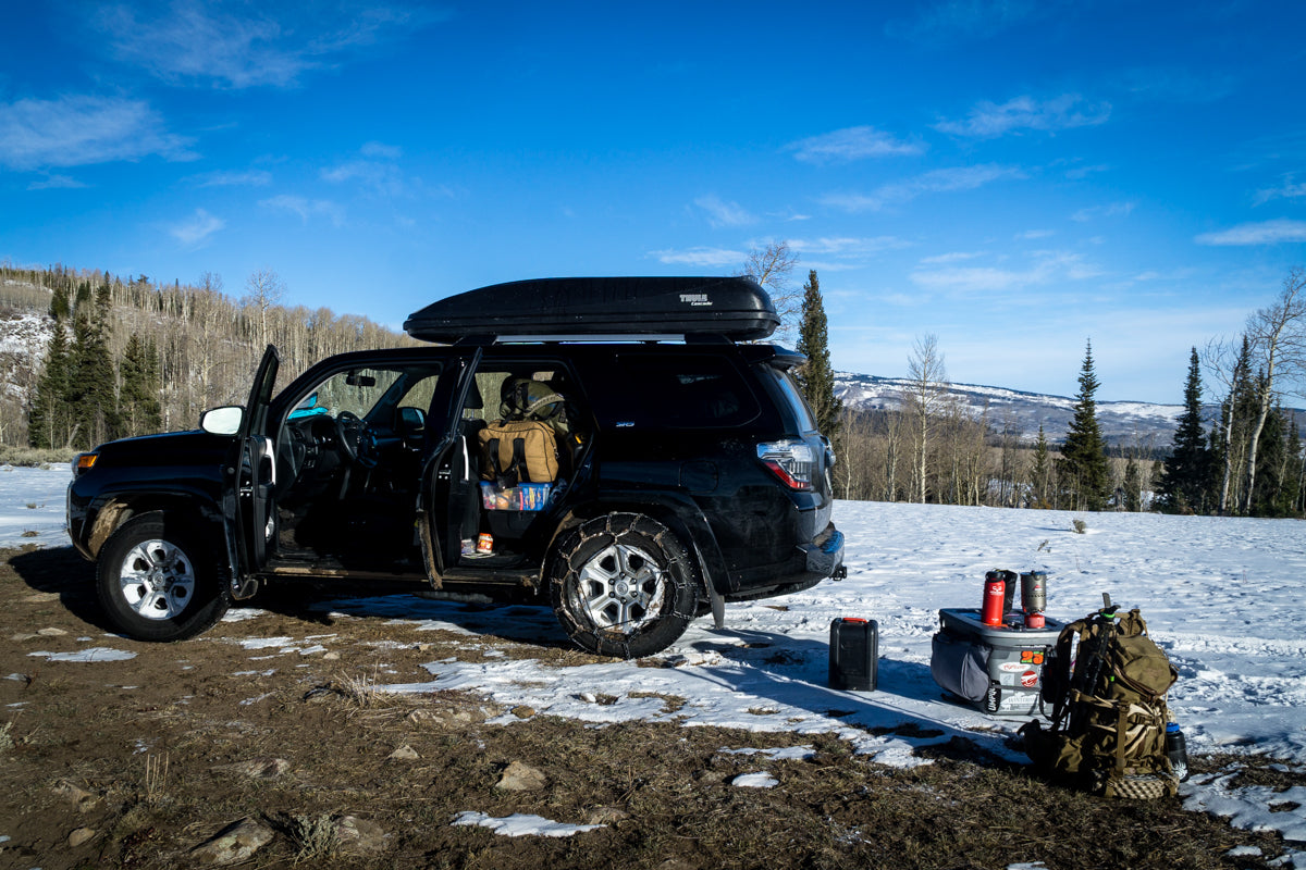 Truck-to-trailhead checklist staging with Ditty Bag organizer, Hunter’s Tarp workspace, and Caribou Gear Waterproof Rifle Cover before a hike
