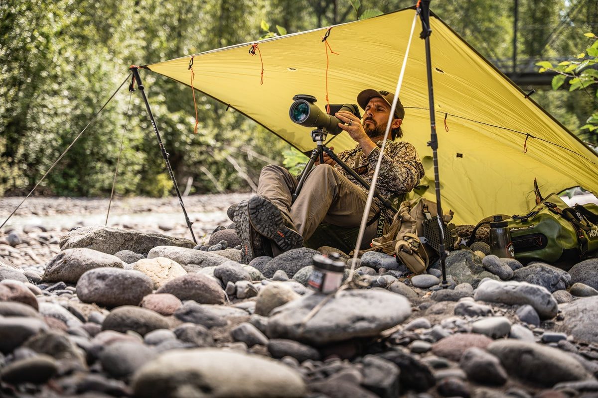 Hunter scouting in wind and spring snow using a Hunter’s Tarp for ground protection and a Ditty Bag to keep essentials organized and dry