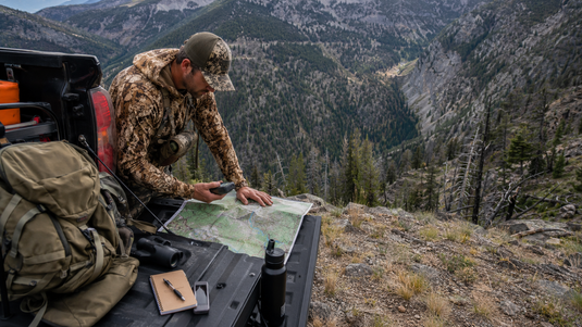 Western hunter reviewing packout route and terrain before an elk hunt in steep mountain country
