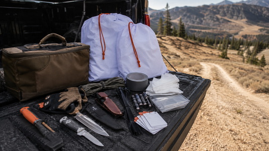 Organized elk hunting kill kit with knives gloves cordage game bags batteries tags and replacement supplies laid out before season